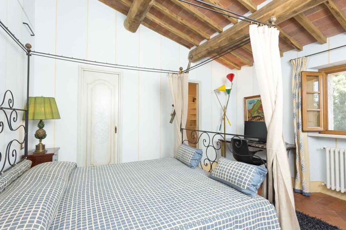 A bedroom with a bed, a desk, and a window.