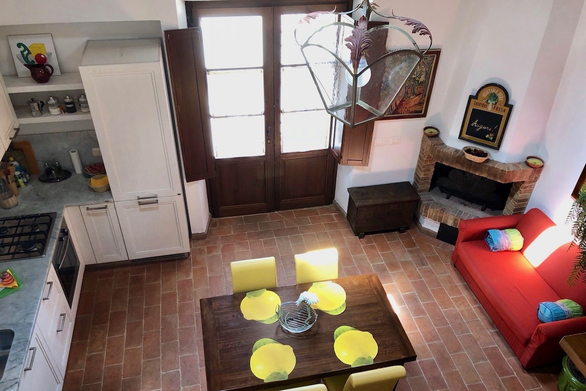 A compact living space with a dining area, a red sofa, a fireplace, and a kitchen area.