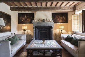 A traditional living room with a fireplace, two sofas, and a coffee table. - Casale degli Ulivi (Rapolano Terme)