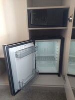 Un refrigerador compacto con panel de control digital, compartimento congelador y dispensador de hielo incorporado.