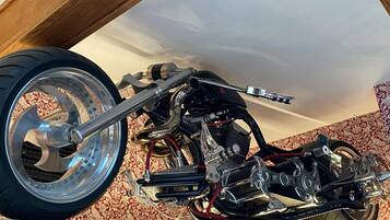 Una motocicleta con detalles cromados y una rueda trasera grande, exhibida en un interior con papel tapiz estampado.