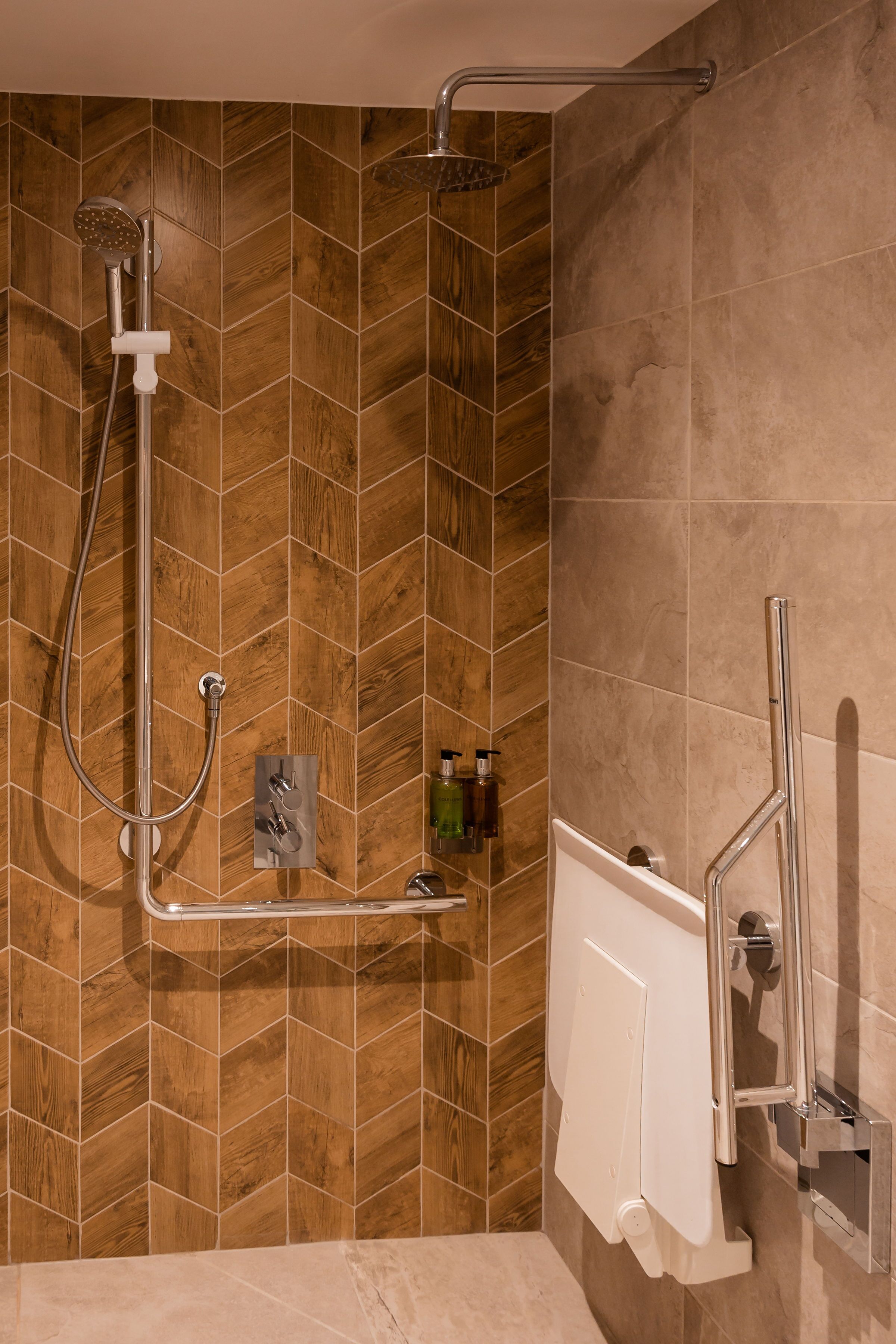 Un espacio de ducha con pared de listones de madera, un cabezal de ducha manual y un grifo empotrado.