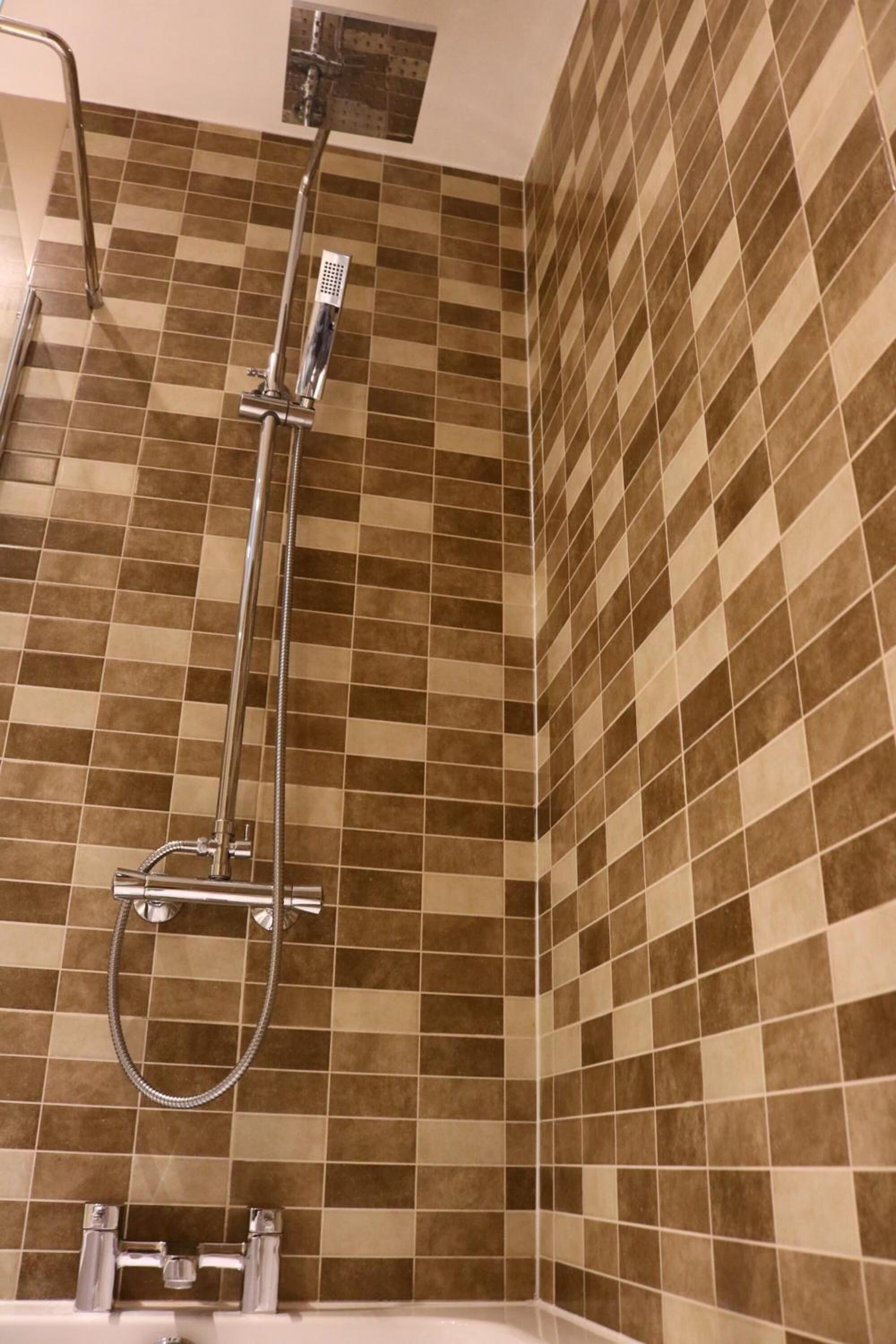 A bathroom with a shower, tiled walls, and a bathtub.