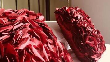 Una cama con una colcha roja estampada de flores y un cojín a juego.