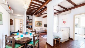A spacious living area with a wooden dining table, chairs, and a bookshelf. - Otranto - WR Apartments (Rome)
