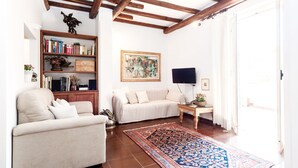 A living room with a sofa, a bookshelf, a painting, and a television. - Otranto - WR Apartments (Rome)
