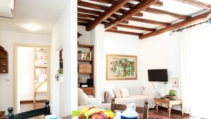 A living room with a wooden ceiling, a sofa, a coffee table, and a TV. - Otranto - WR Apartments (Rome)