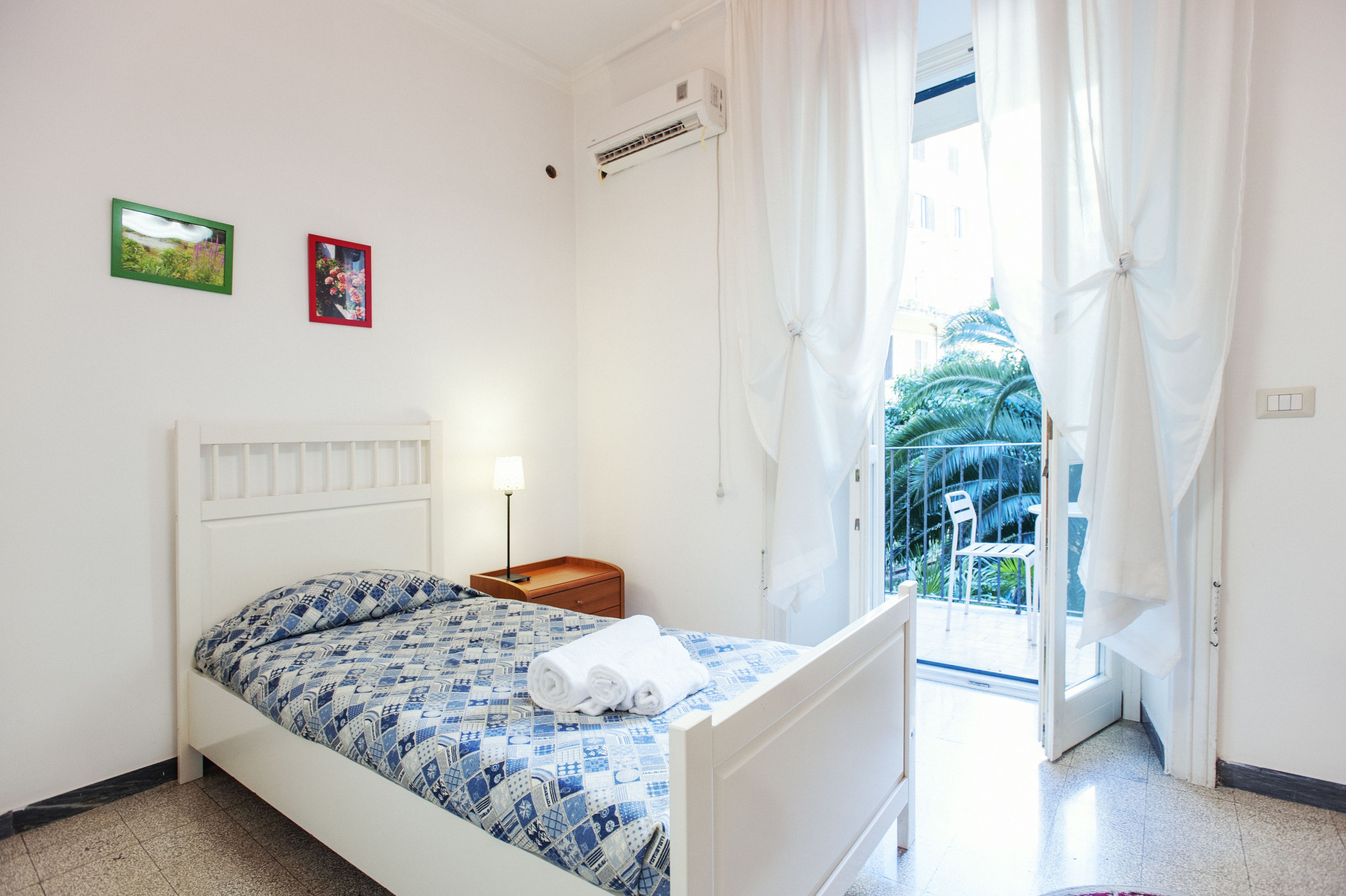 Ein Schlafzimmer mit einem Bett, einem Nachttisch, einer Lampe und zwei gerahmten Bildern an der Wand.
