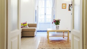 A hallway with a beige sofa, a wooden table, and a vase with flowers. - Palestrina - WR Apartments (Rome)