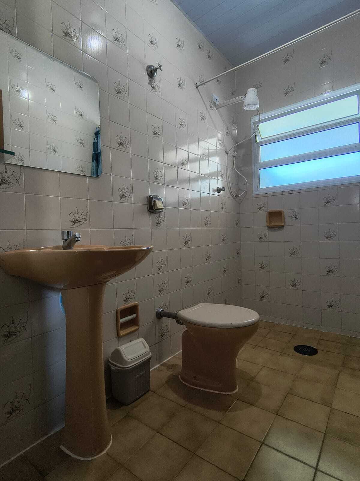 Une salle de bain avec un lavabo sur colonne, des toilettes et une douche.