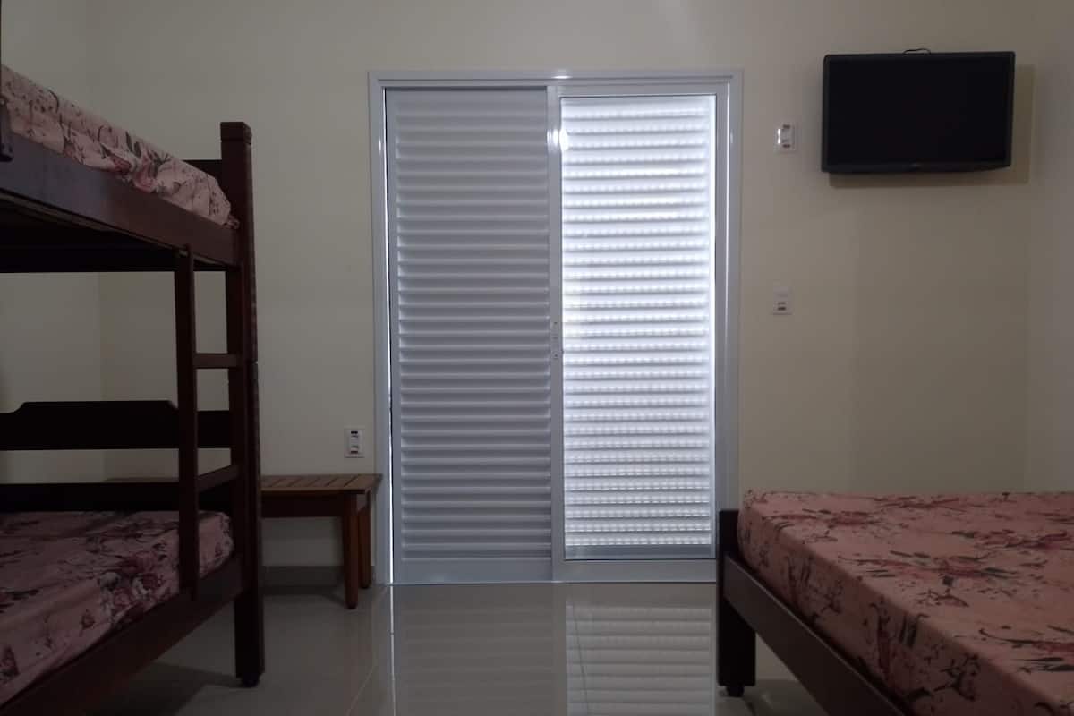 Quarto com beliches, porta deslizante e televisão de tela plana na parede.