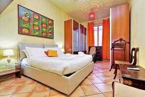 Une chambre d’hôtel avec un lit, un bureau, une chaise, une lampe et un tableau au mur.