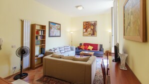 A living room with a sofa, a coffee table, a bookshelf, and a floor lamp. - Romalibera - WR Apartments (Rome)