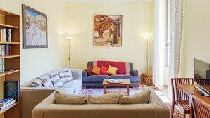 A living room with a sofa, a coffee table, a TV, and a bookshelf. - Romalibera - WR Apartments (Rome)