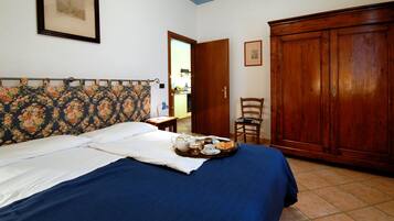 Ein Schlafzimmer mit einem Bett, einem Holzschrank, einem Stuhl und einem kleinen Tisch mit Frühstücksgegenständen.