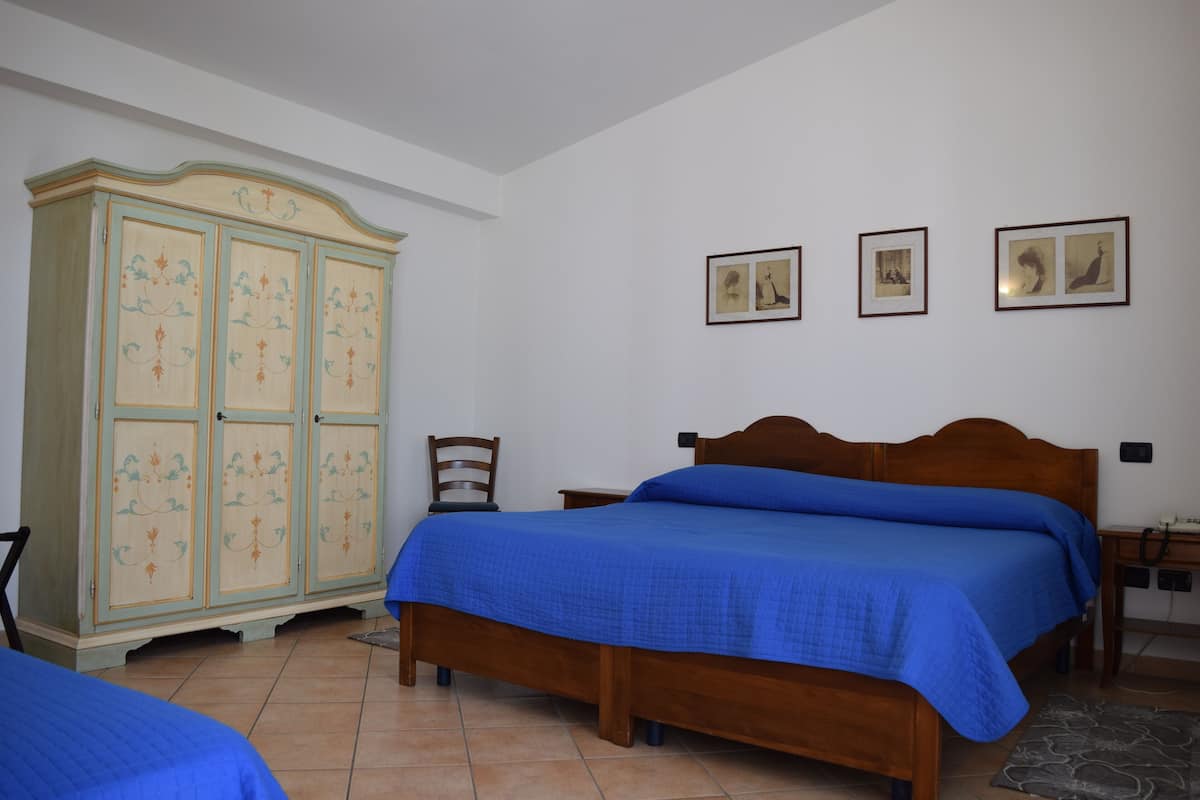 A bedroom with a wooden bed, a wardrobe, and three framed pictures on the wall.