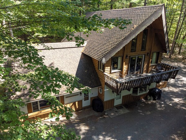 A cabin with a balcony, a porch, and a covered outdoor seating area.