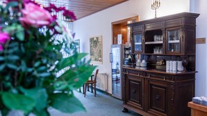 Una cocina con un armario de madera oscura, una mesa de comedor con sillas y un jarrón de flores.