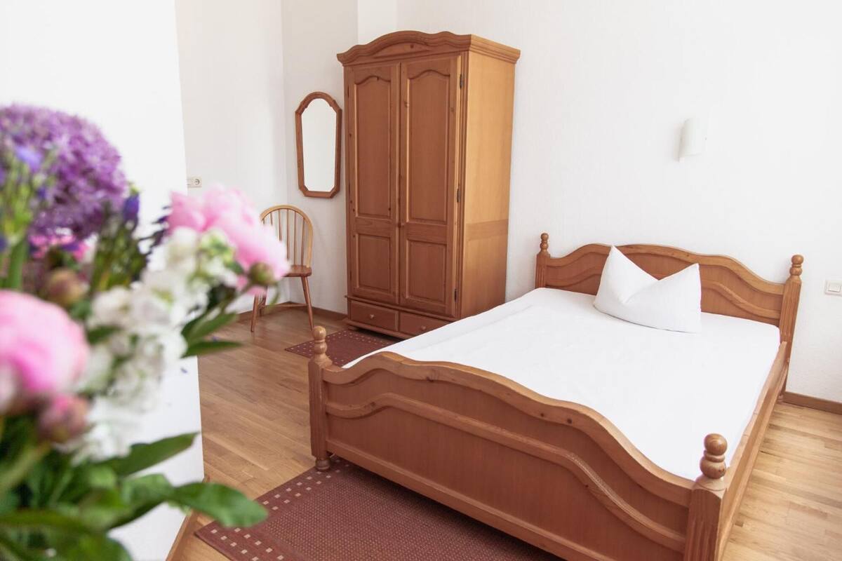 Un dormitorio con cama de madera, armario, silla y espejo.