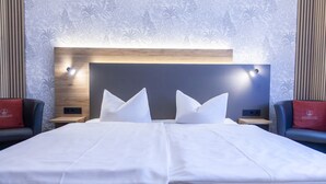 Habitación de hotel con una cama grande, dos mesitas de noche y un cabecero con iluminación integrada.