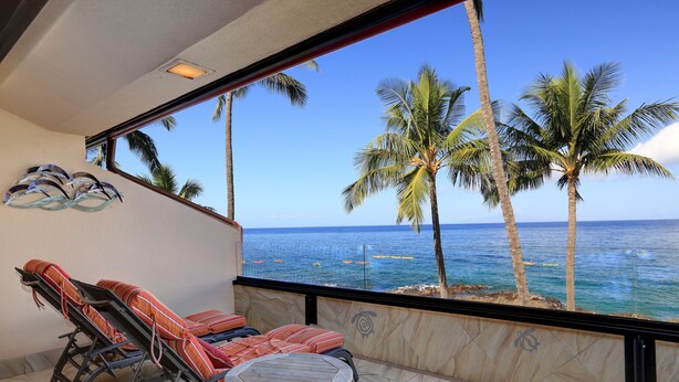Un balcone con vista sull'oceano, palme e pavimento piastrellato.