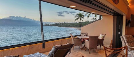 A balcony with wicker furniture, a table, and a view of the ocean.