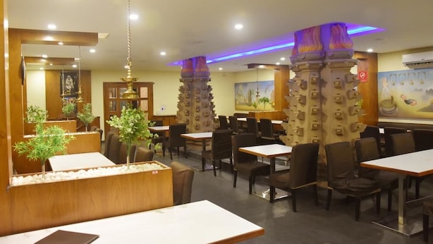 Un restaurante con mesas y sillas de madera, pilares decorativos y un mural en la pared.