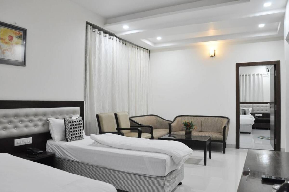 Una habitación de hotel con una cama, dos sillones, un sofá, una mesita y un espejo.