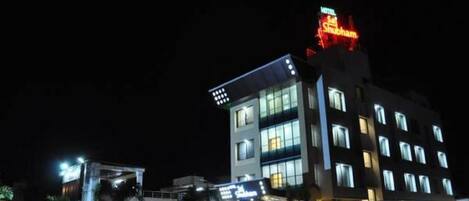 A hotel with a modern design, featuring multiple floors and illuminated windows.