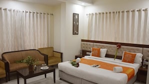 Una habitación de hotel con una cama, un sofá, una mesita de café y cortinas.