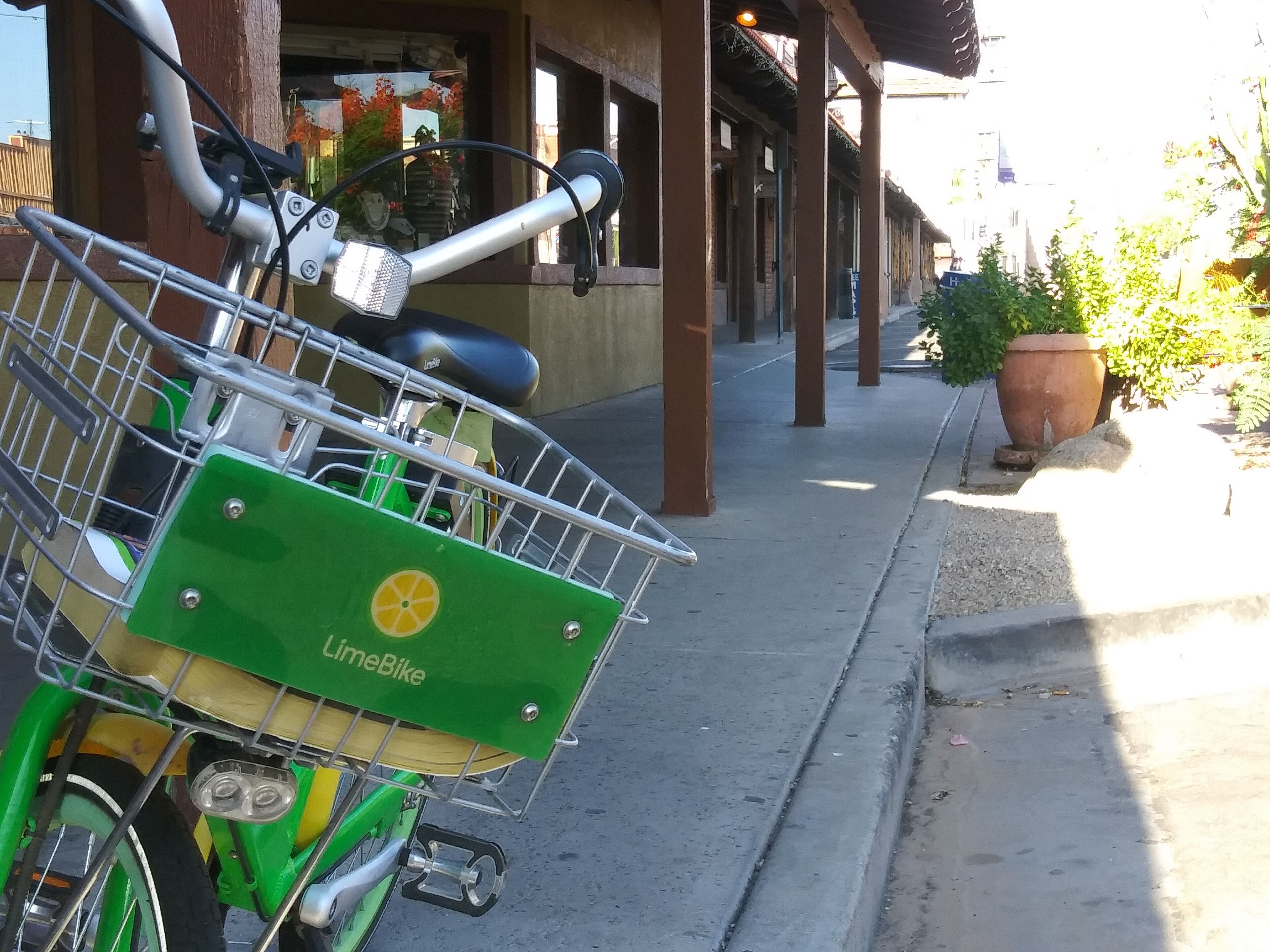 Una bicicletta LimeBike parcheggiata su un marciapiede vicino a un edificio con un negozio.