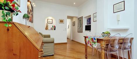 A spacious room with a wooden dining table, clear plastic chairs, and a wooden cabinet.