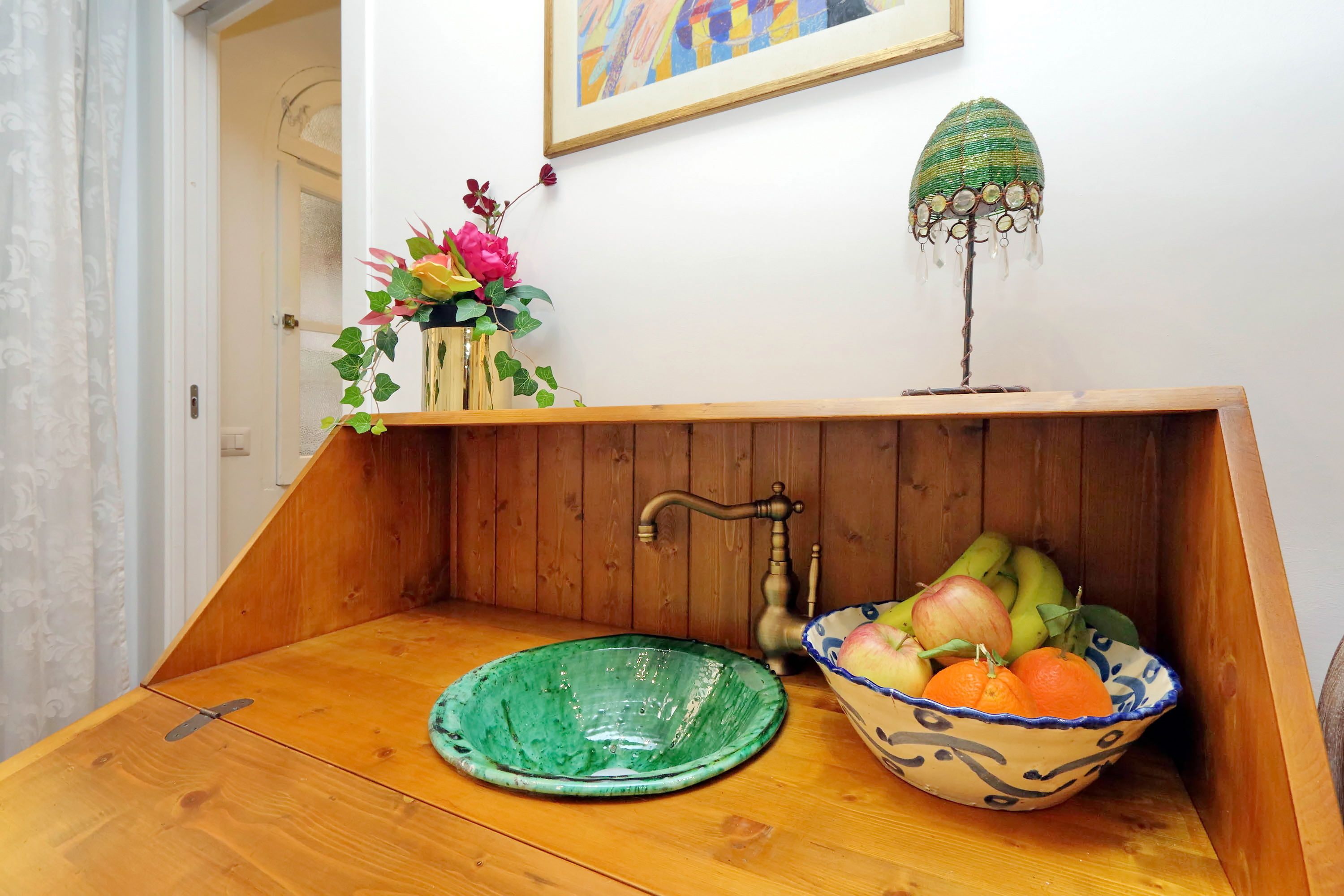 A wooden bench with a green bowl and a decorative lamp.