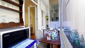 Une cuisine compacte équipée d’un four à micro-ondes, d’une table à manger avec des chaises, et offrant une vue sur un aquarium à travers une fenêtre.