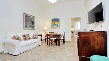 Una sala de estar con un sofá blanco, una mesa de comedor de madera y dos cuadros en la pared.