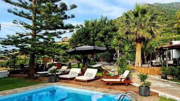Una piscina al aire libre, sombrillas, sillones reclinables de piscina