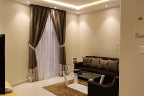 A modern living room with a dark brown sofa, a glass coffee table, and a patterned rug. - AL Muhaidb Residence Abha - Economic (Abha)