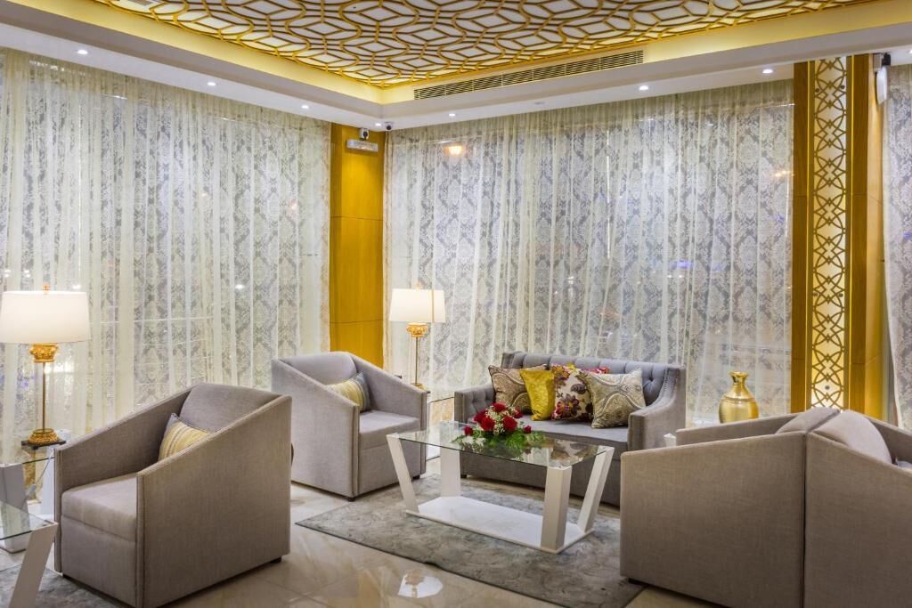 Una sala de estar moderna con un sofá, dos sillones, una mesa de centro de vidrio y lámparas decorativas.