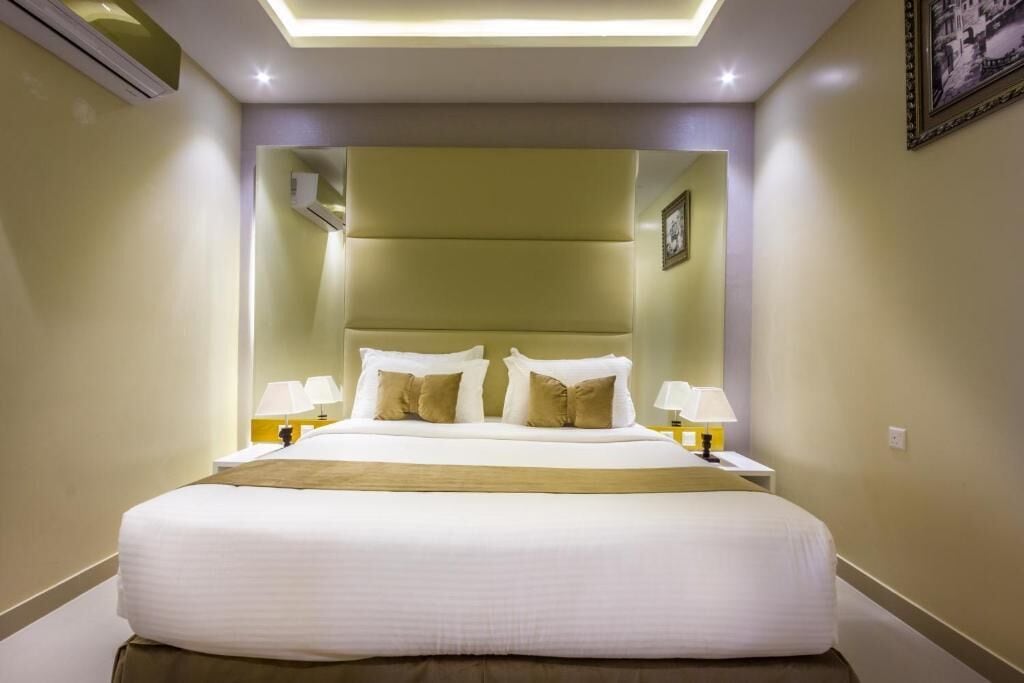 Een hotelkamer met een groot bed, nachtlampjes en een ingelijst schilderij aan de muur.