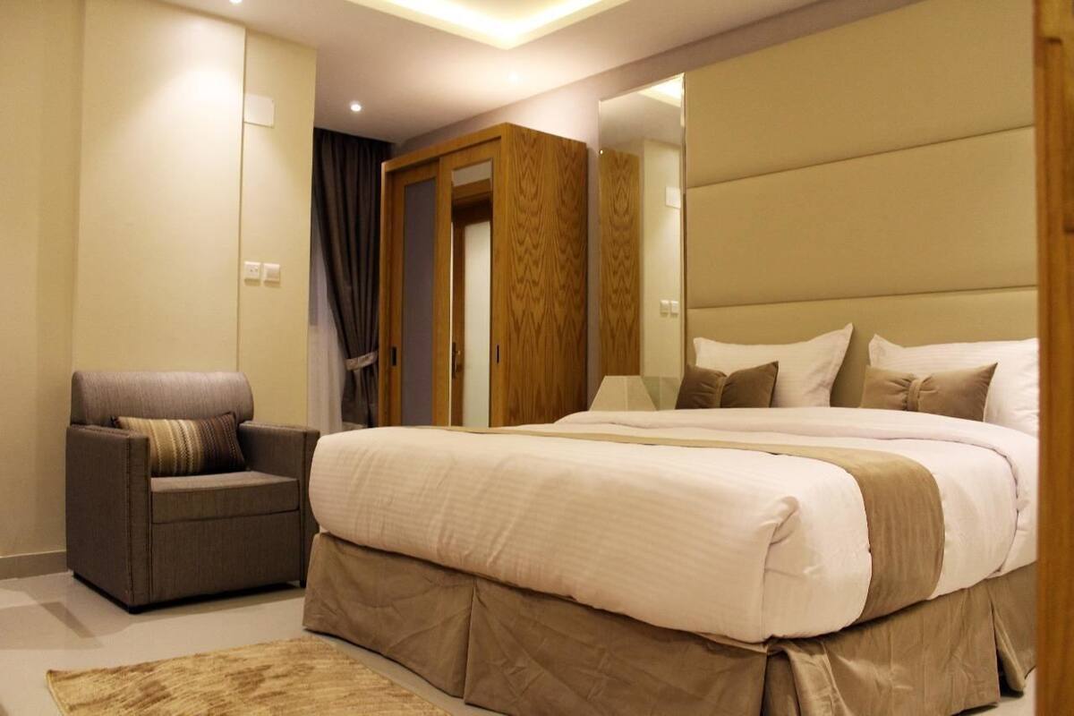 Ein modernes Schlafzimmer mit einem großen Bett, einer Sitzecke und einem Kleiderschrank.