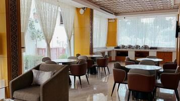A hotel lobby with a dining area, multiple seating arrangements, and a decorative ceiling.
