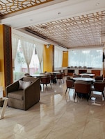 A hotel lobby with a dining area, multiple seating arrangements, and a decorative ceiling.