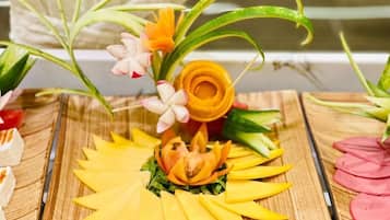 A wooden table with a decorative arrangement featuring a yellow flower and green leaves.