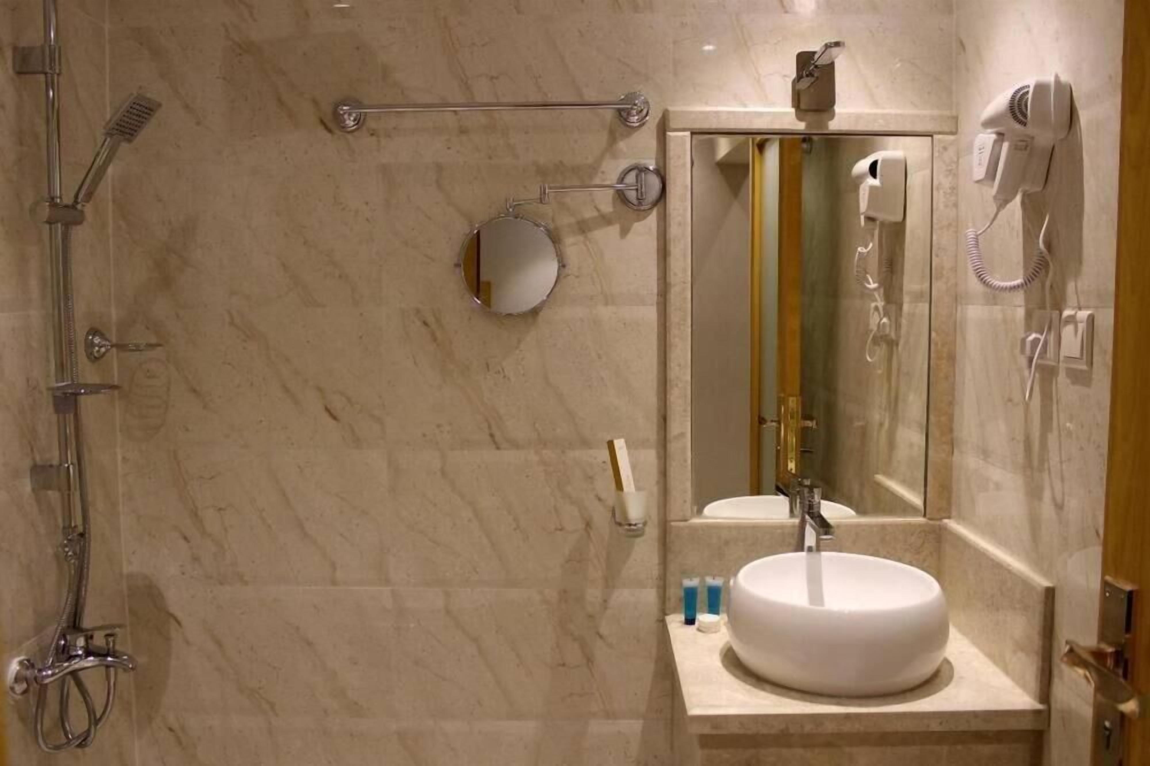 Un baño con ducha, lavabo, espejo y secador de pelo.
