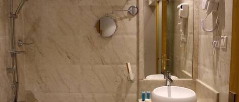 Un baño con ducha, lavabo, espejo y secador de pelo.