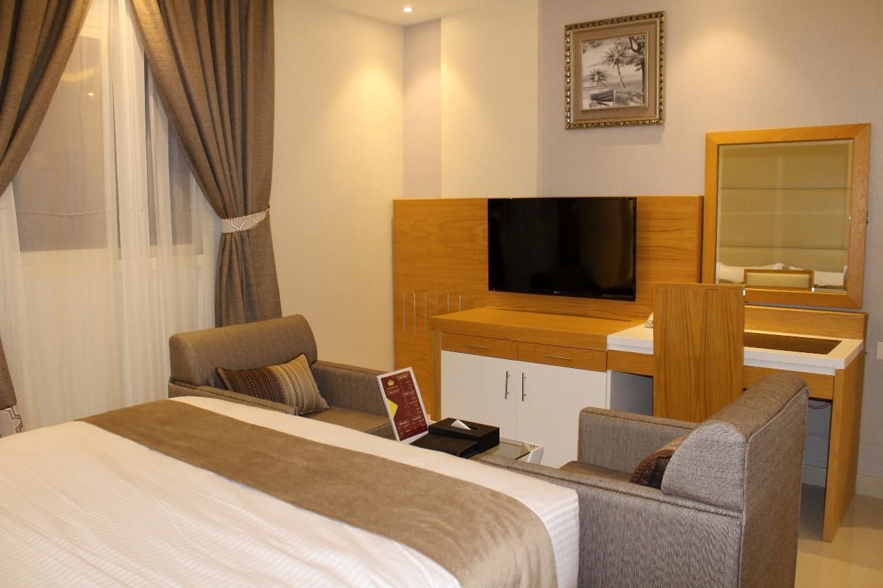Une chambre d’hôtel avec un lit, un bureau, une télévision et un miroir.
