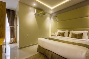 A modern hotel room with a large bed, a bedside table, a lamp, and an air conditioning unit. - AL Muhaidb Residence Abha - Economic (Abha)