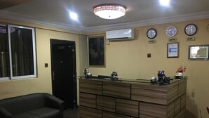 Una zona de recepción con un mostrador de madera, un sofá de cuero negro y relojes en la pared.