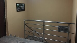 Una escalera con barandillas de metal, una lámpara en el techo e imagen enmarcada en la pared.