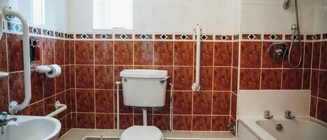 Et badeværelse med toilet, vask og badekar.
